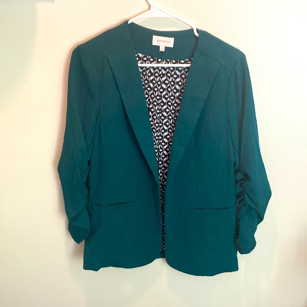 Skies are blue emerald green with black-and-white design inside blazer.